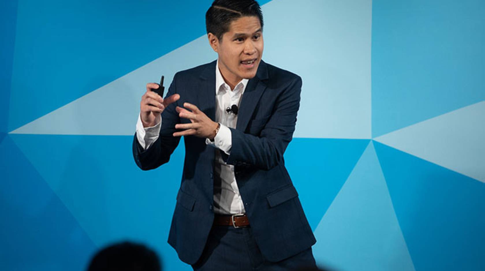 Image shows person speaking on a stage