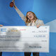 image shows person holding giant check and a trophy for the grad slam